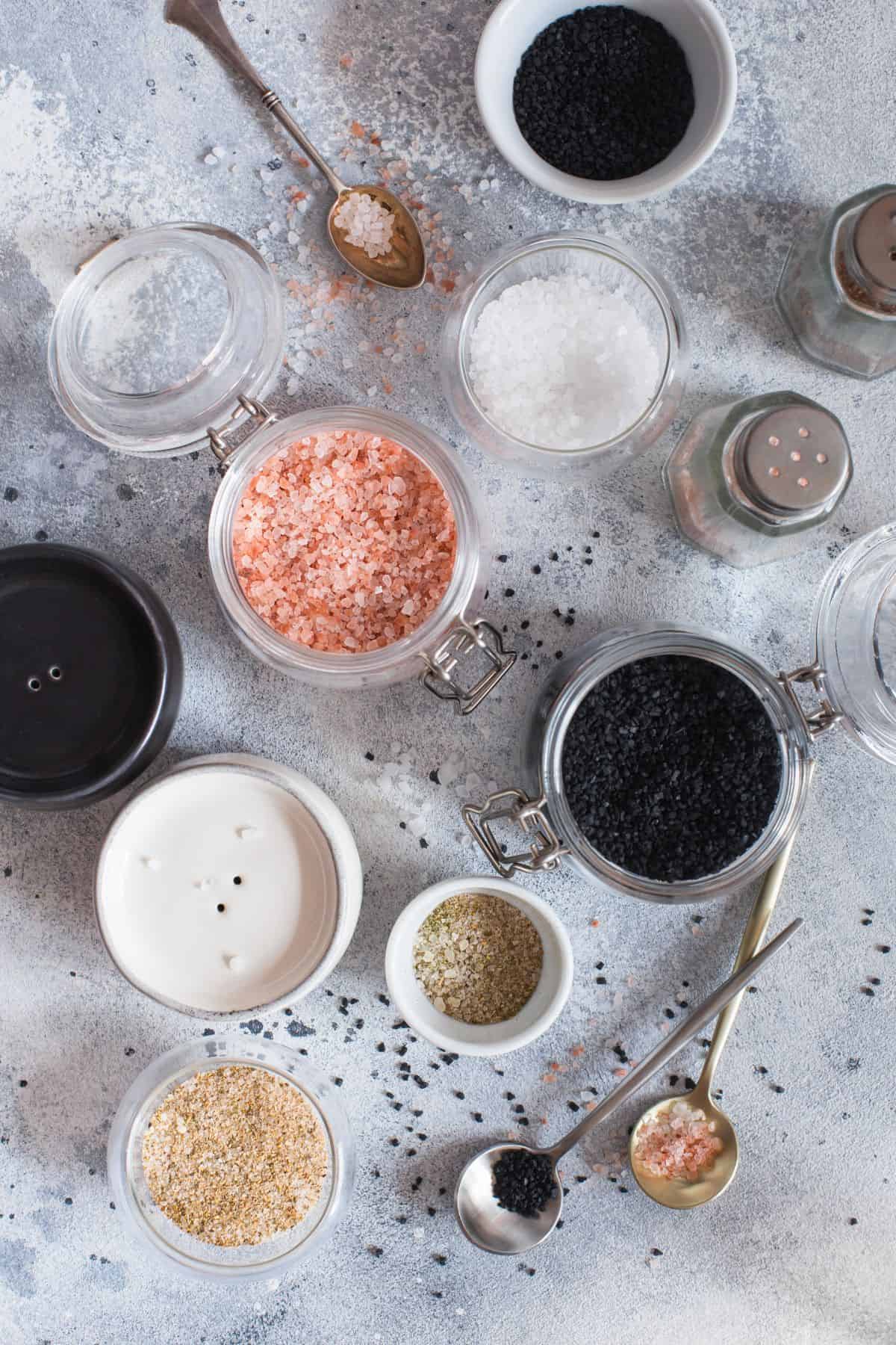 Overhead photo of different kinds of salts on a gray background.