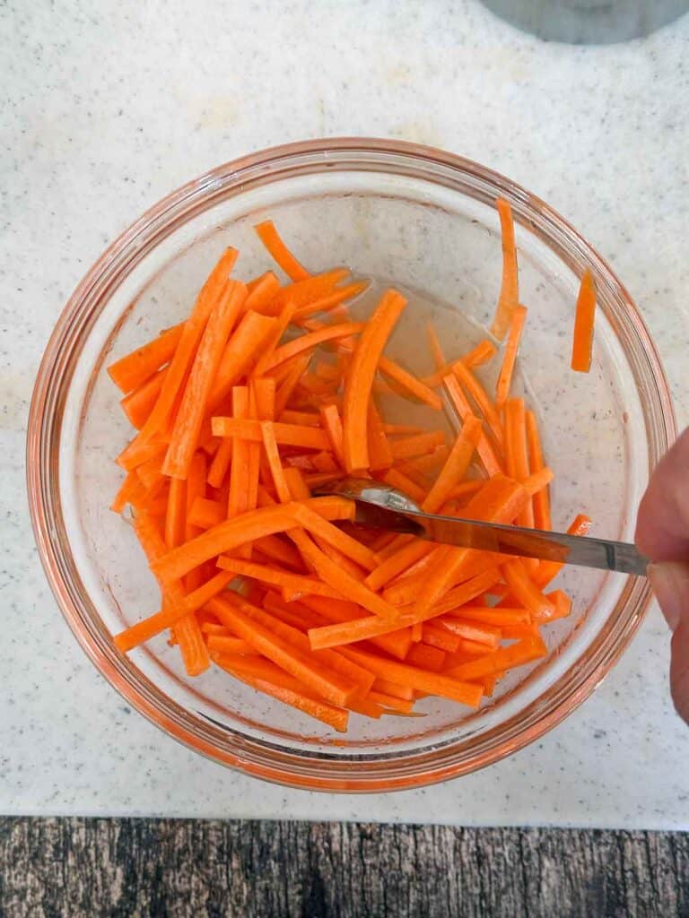 Mixing carrots with pickling liquid for Bánh Mì hot dogs.