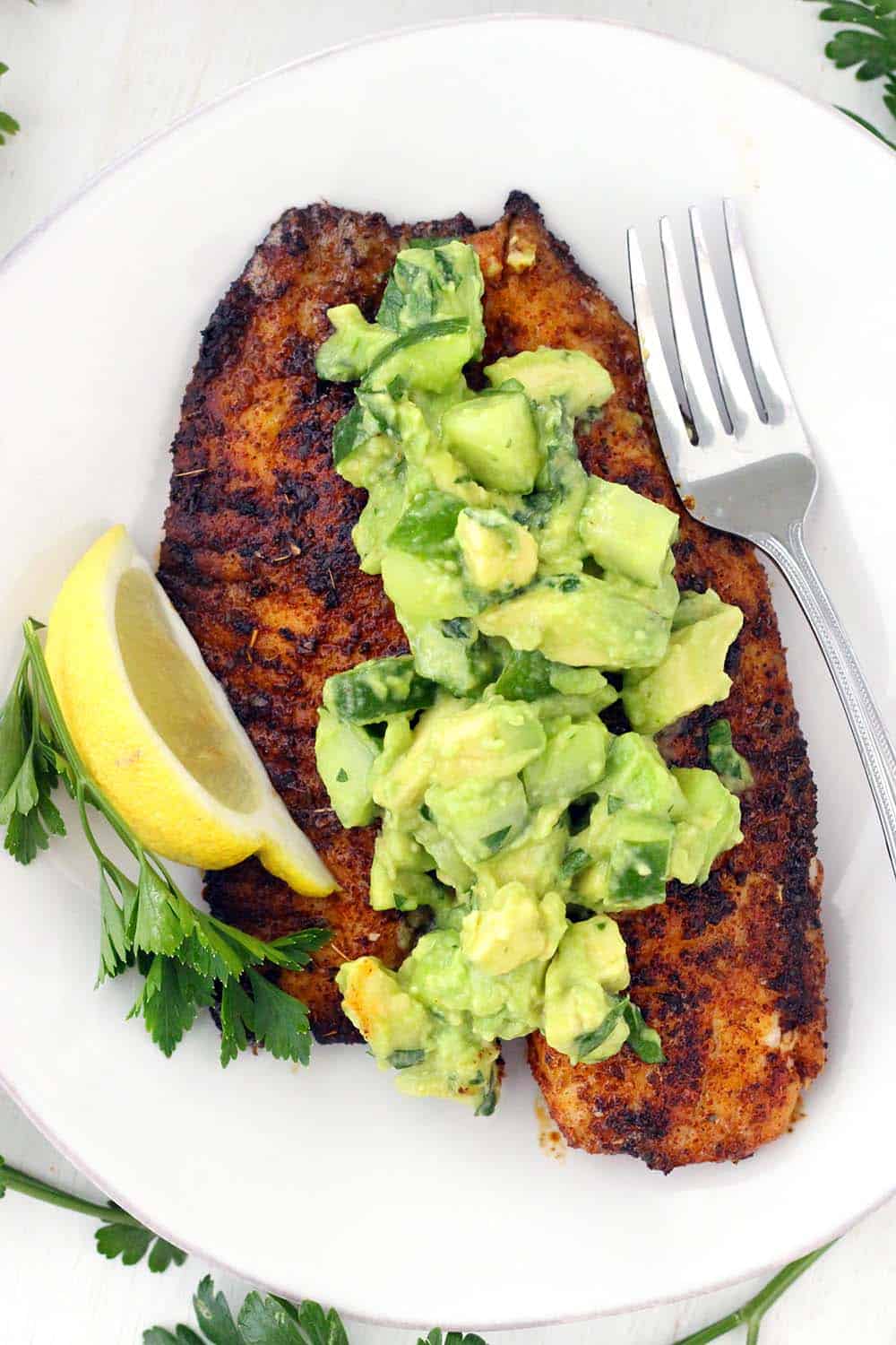 This super flavorful Blackened Tilapia comes together in less than 10 minutes!! Topped with a cool and refreshing avocado cucumber salsa, this is the perfect quick and easy low-carb recipe. Paleo, gluten free, and whole30 compliant.