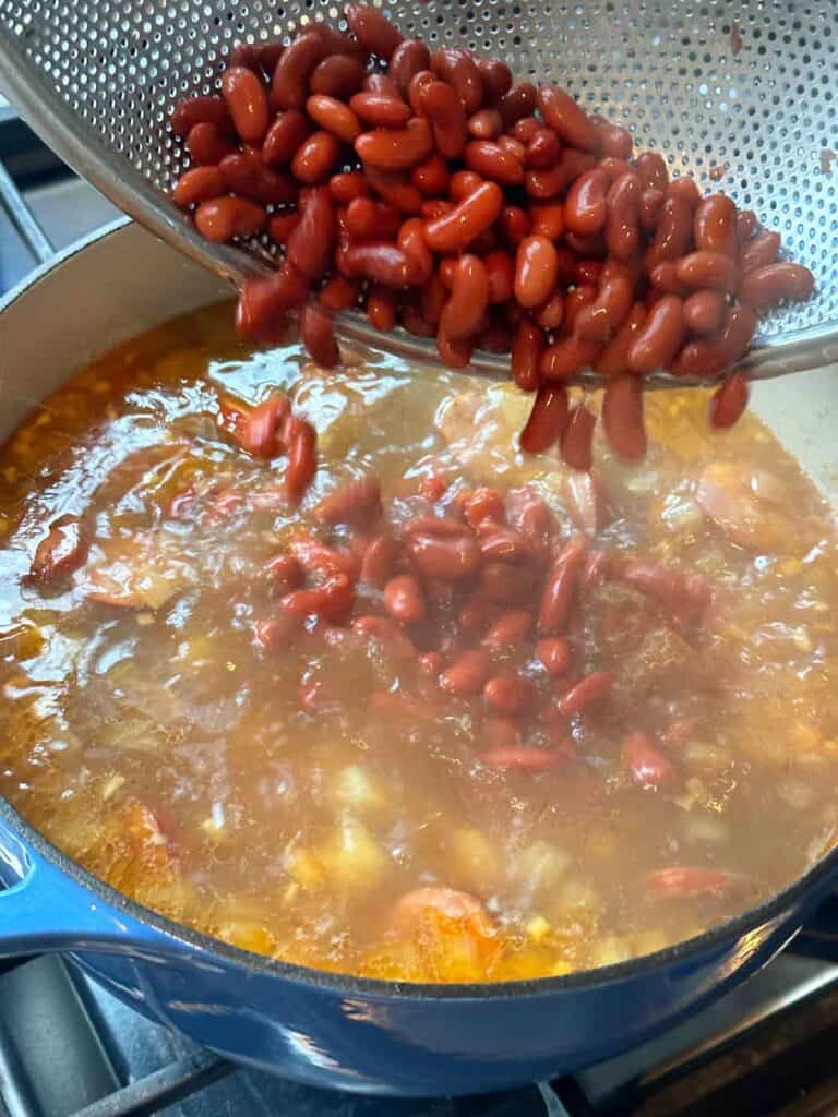 Adding red kidney beans to caldo verde soup.