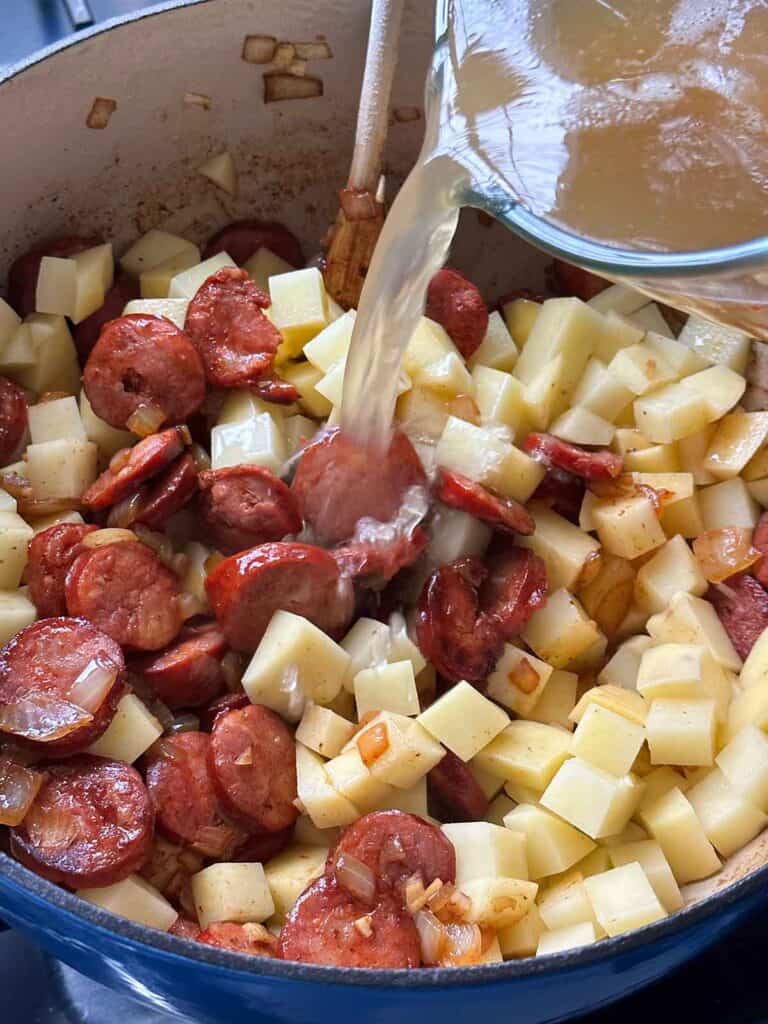 Adding broth and water to caldo verde.