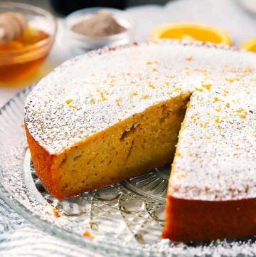 Orange olive oil cake with a slice taken out.