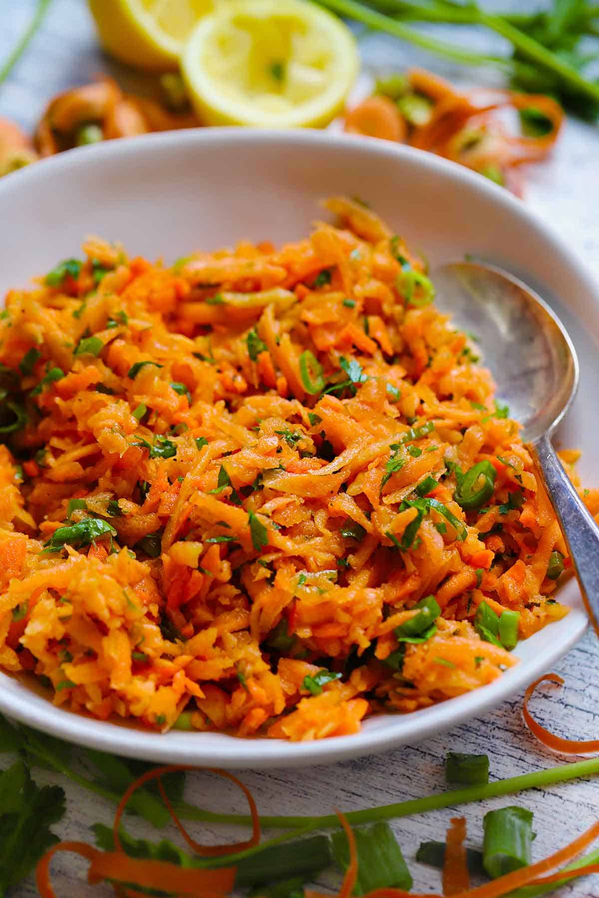 Side view close up of shredded carrot salad with herbs.