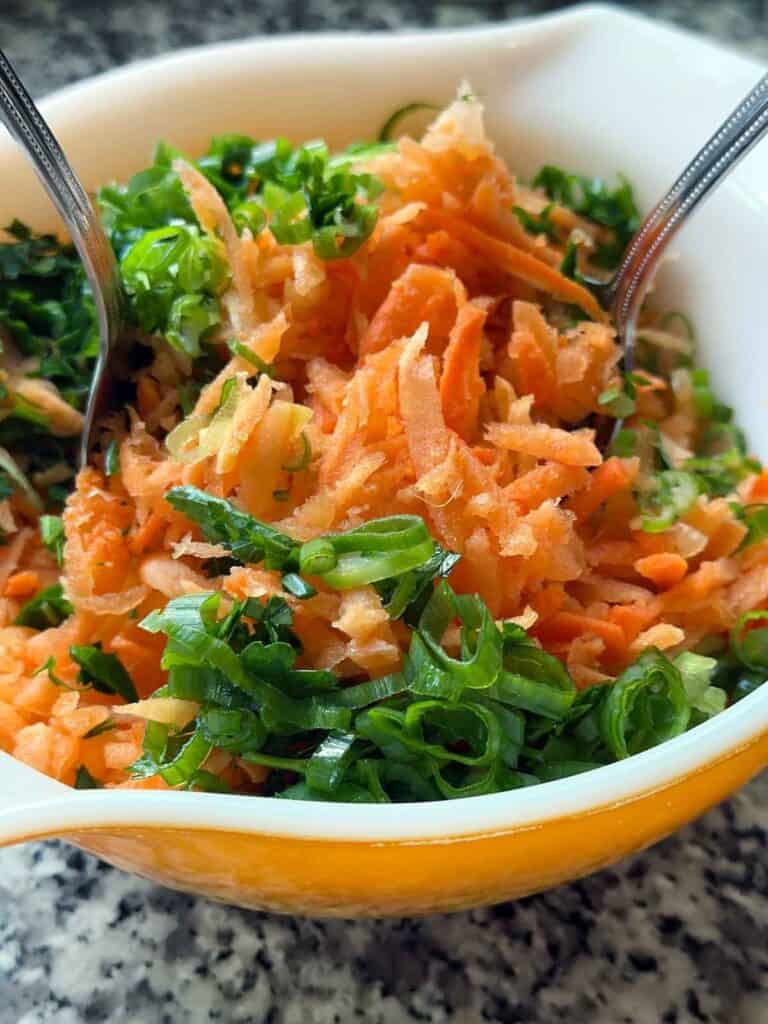 Tossing a carrot salad together in a bowl.