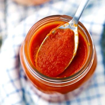 A jar of homemade chipotle enchilada sauce with a spoon in it.