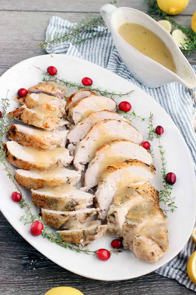 A white platter with sliced turkey and gravy.