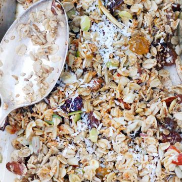 Close up bird's eye view of a layer of granola, with a silver antique spoon on the side.