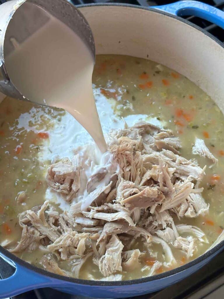 Adding half and half and shredded chicken to soup.