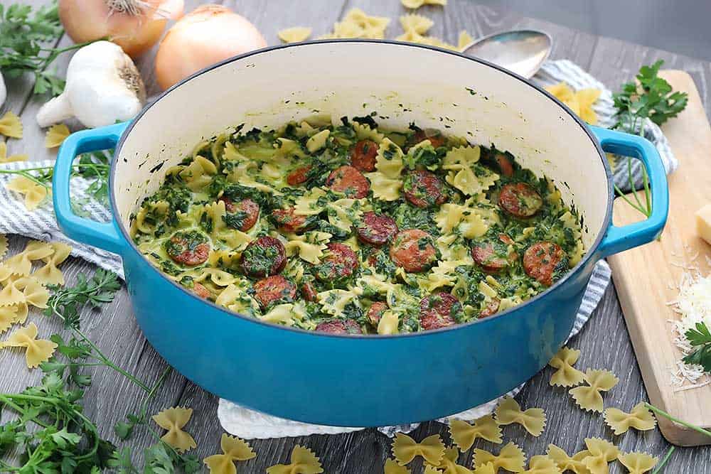 Horizontal photo of a blue Dutch oven with pasta inside.