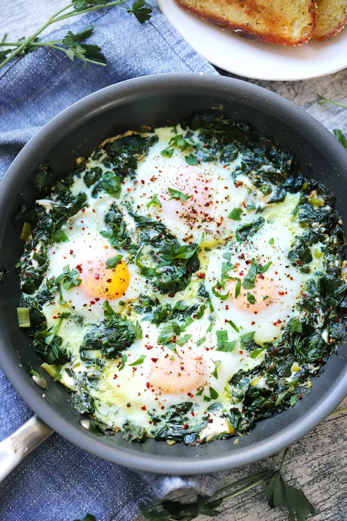 Creamy spinach and eggs in a skillet.