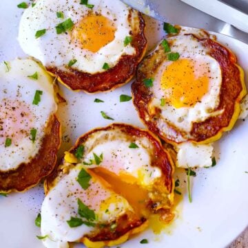 Square photo of delicata squash egg cups on a white plate.