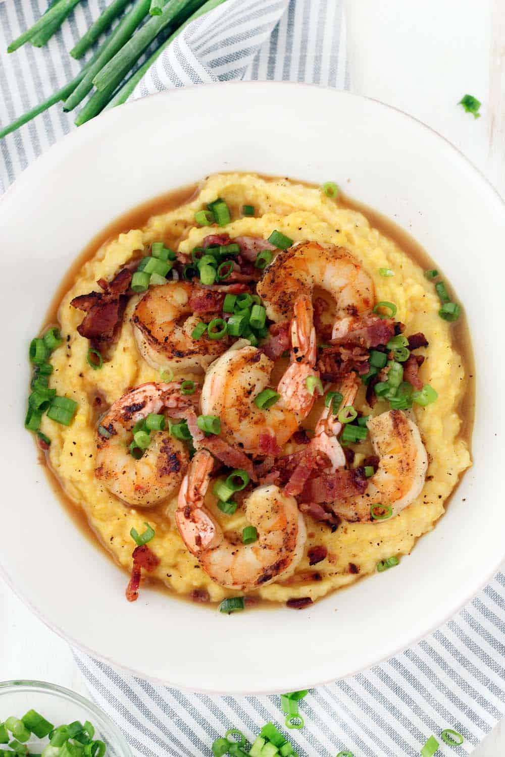 This classic Shrimp and Grits recipe is easy to make and is such delicious Southern comfort food! The cheesy grits are cheap and gluten free, and make an excellent base for the flavorful shrimp and crumbled bacon.