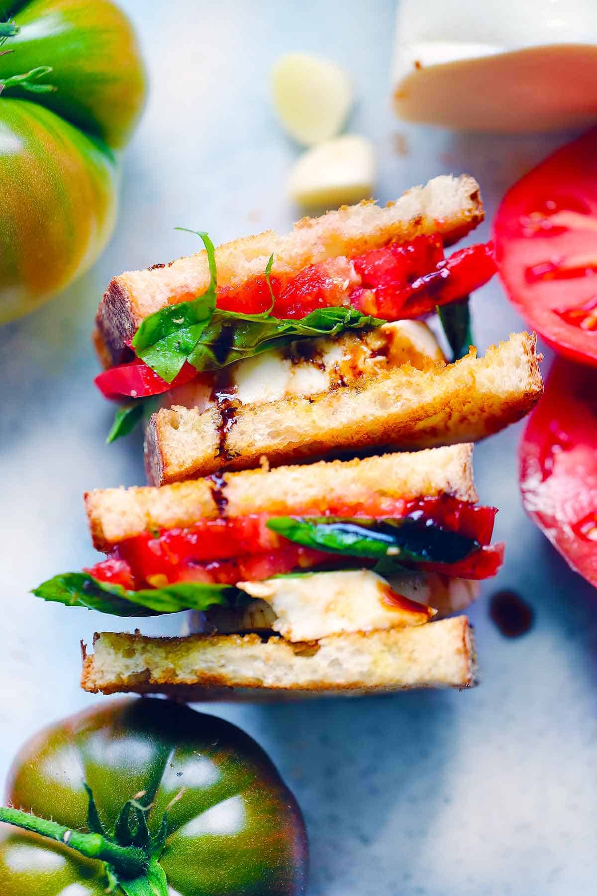 A caprese sandwich cut in half drizzled with balsamic glaze.