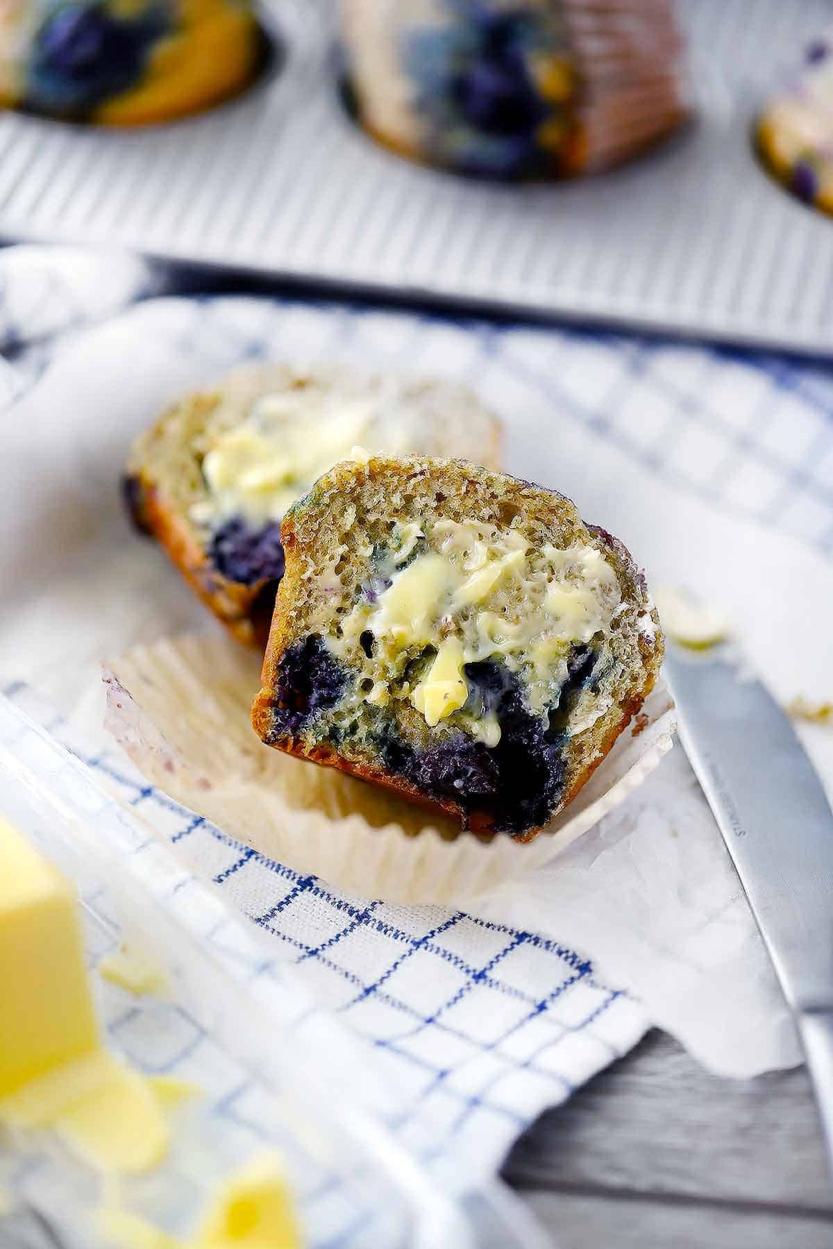Blueberry muffin sliced in half with butter on it.