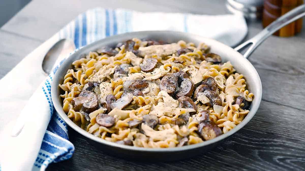 Chicken and mushroom stroganoff in a skillet on a towel.