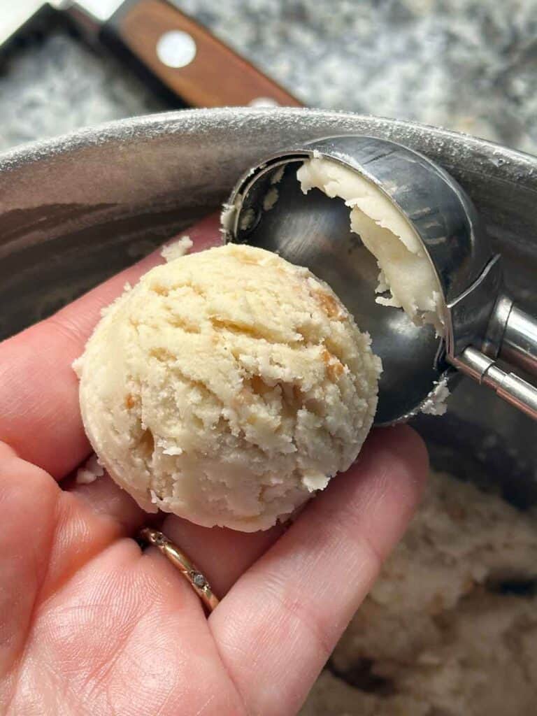 Using a cookie scoop to measure out portions of kourabiedes dough.