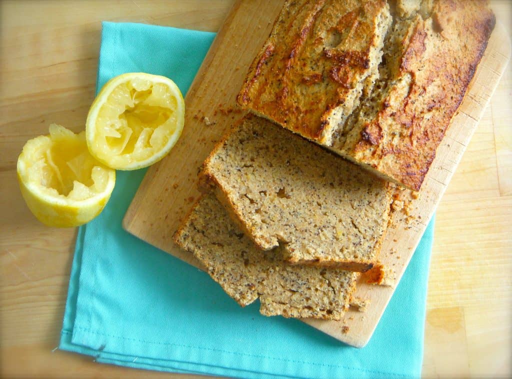 Bird's eye view of poppy seed loaf, with two slices cut off and squeezed lemon halves on the side.