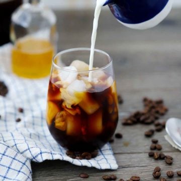 Pouring whole milk into an iced coffee.