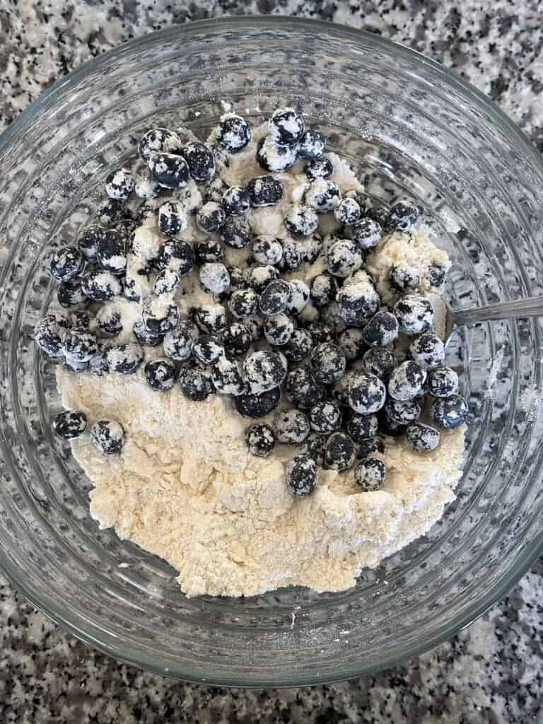 Mixing blueberries into scone dough.