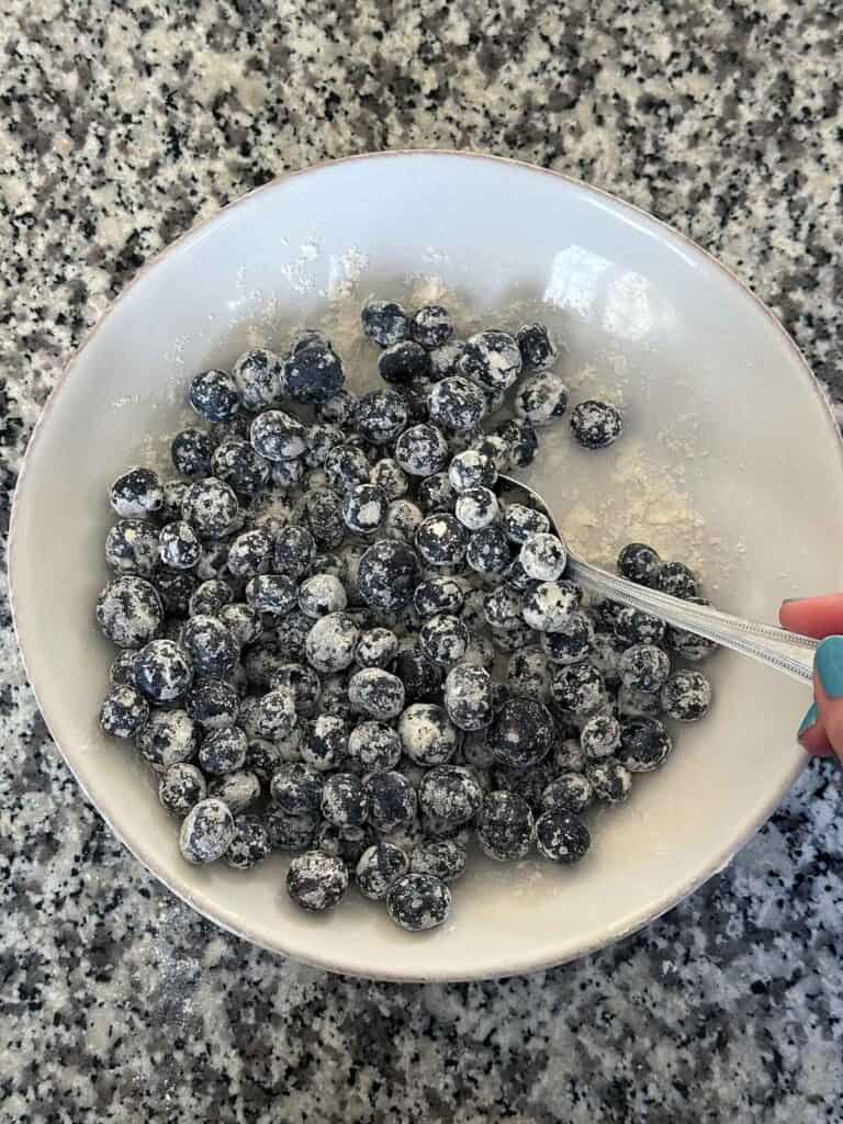 Tossing fresh blueberries with flour.