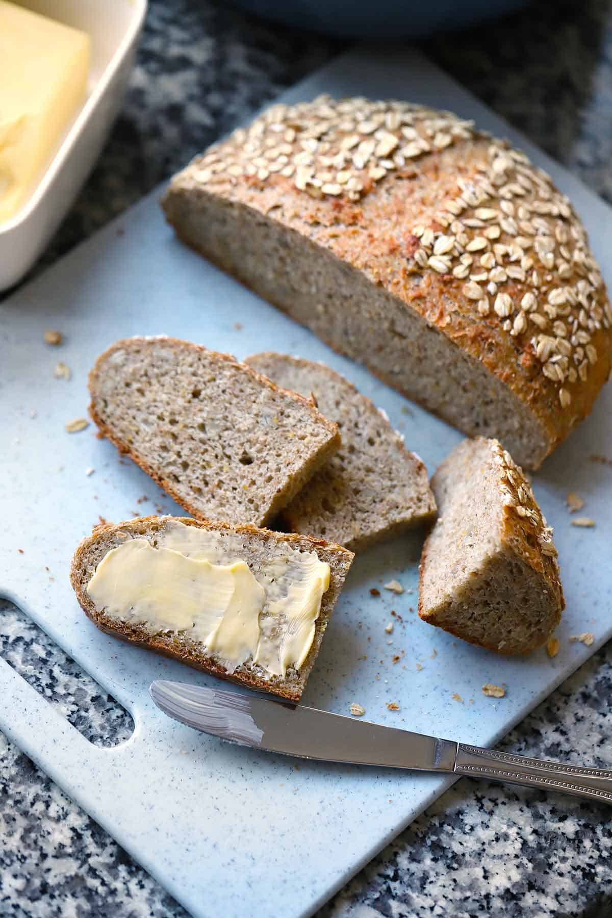 Overhead view of sliced multigrain no knead bread with butter on one slice.