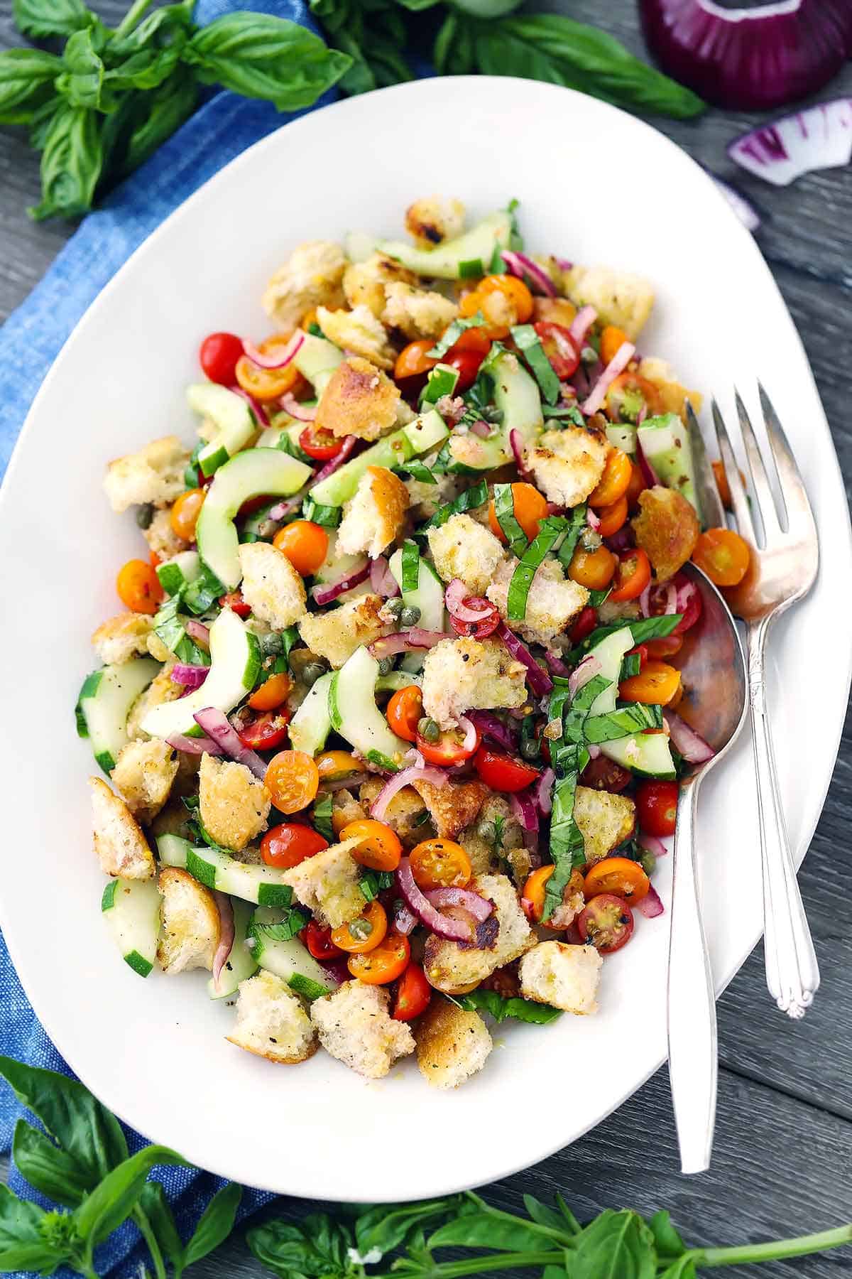 A platter of panzanella, or Italian Bread Salad, with a fork and spoon.