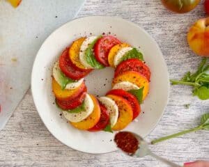 Sprinkling a peach caprese salad with Aleppo pepper.