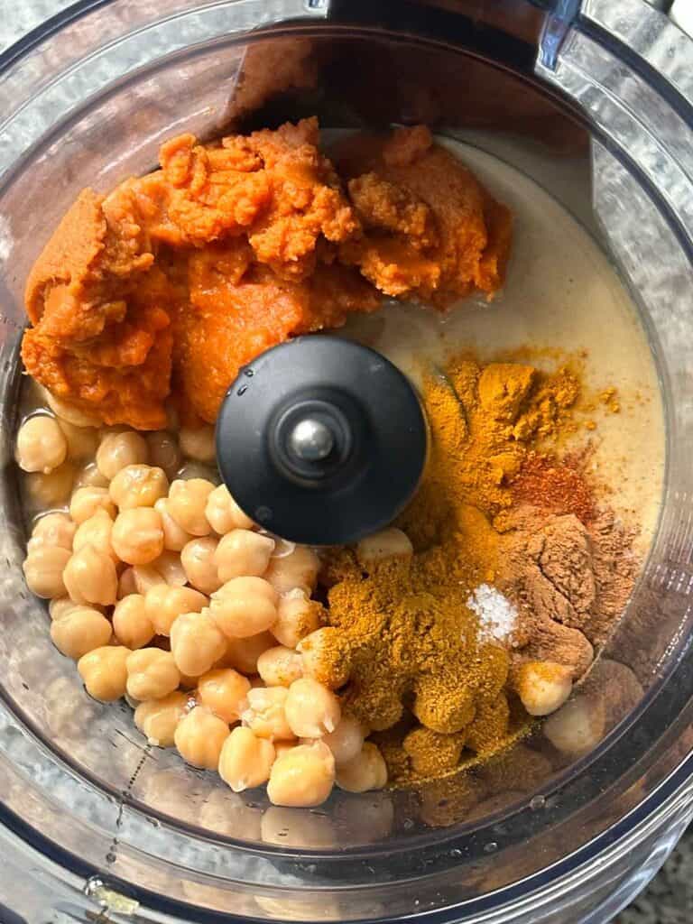The ingredients for pumpkin hummus in a food processor.