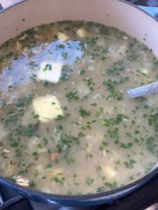 Adding pats of butter to finished clam chowder.