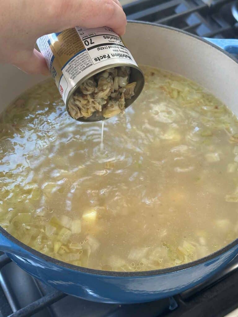 Adding canned clams to chowder.