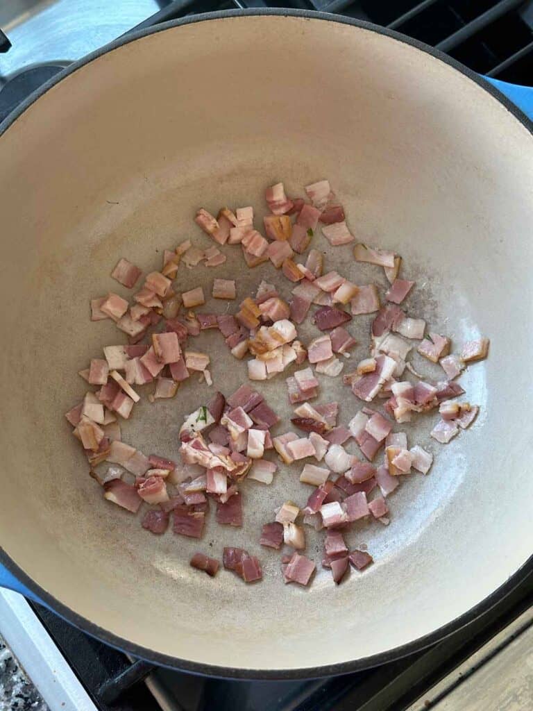 Cooking chopped bacon in a Dutch oven.