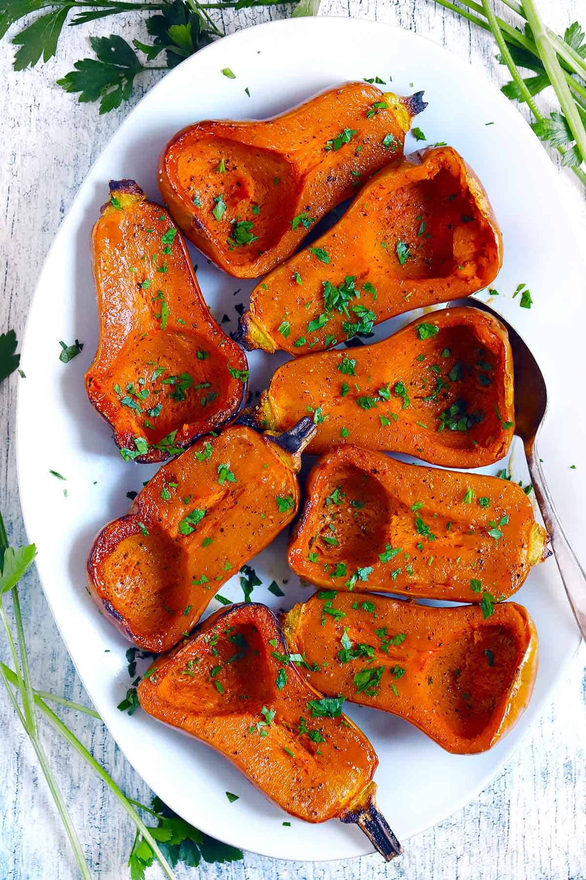 Overhead photo of a platter of roasted honeynut squashes garnished with parsley.