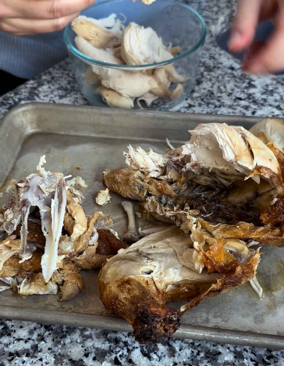 Showing removing the meat from a rotisserie chicken, to prepare a carcass for making homemade broth.