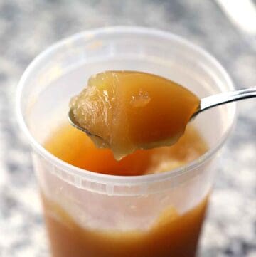 Square photo of a spoonful of cold bone broth that has gelled up from the collagen.