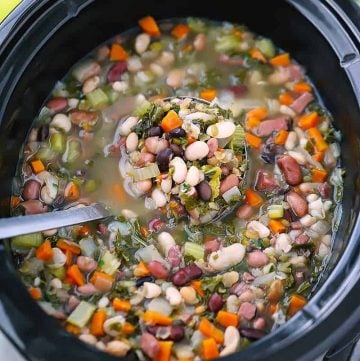 A ladle in a slow cooker with 15 bean soup.
