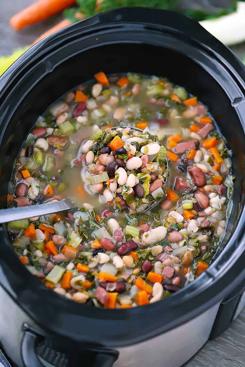 A ladle in a slow cooker with 15 bean soup.