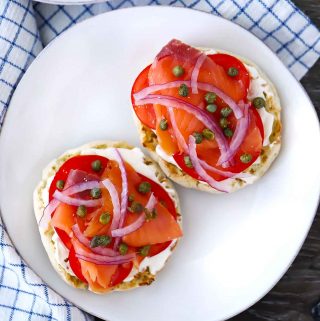 Overhead photo of a smoked salmon english muffin with cream cheese, capers, tomatoes, and red onion