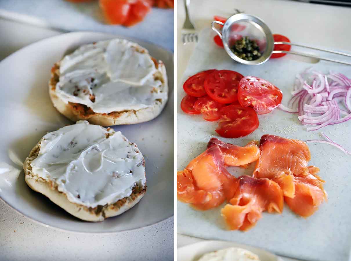 Cream cheese on an english muffin, smoked salmon, tomatoes, capers, and red onion on a cutting board