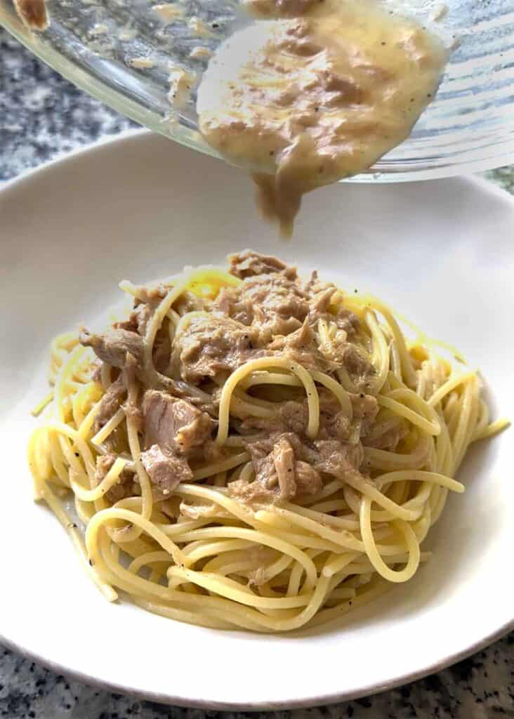 Topping a bowl of spaghetti with remaining tuna and sauce from the bottom of the bowl.