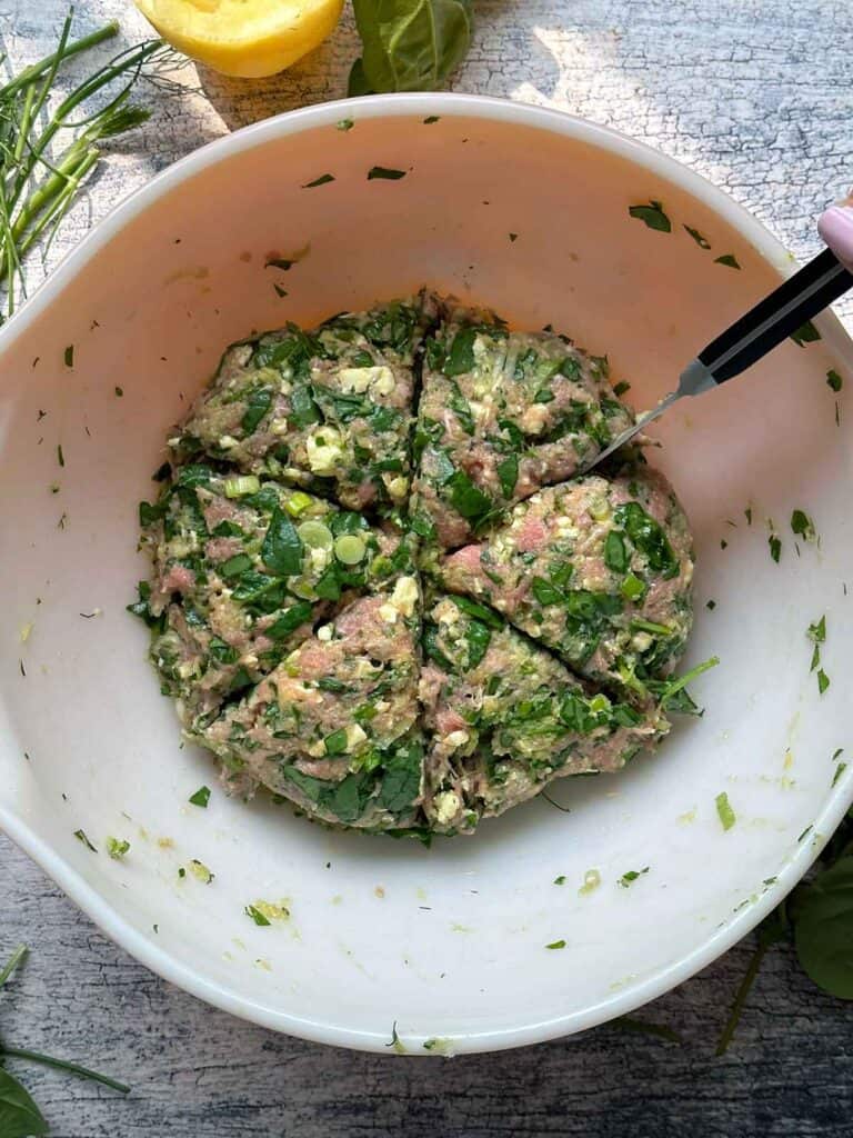Overhead photo showing cutting burger mixture into sixths evenly with a knife before forming the patties.