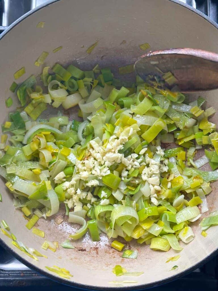 Sautéing leeks and garlic in olive oil in a Dutch oven as a spring soup base.