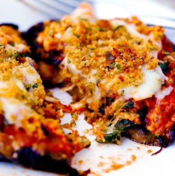 A stuffed portobello mushroom cut in half with cheese and breadcrumbs on top.