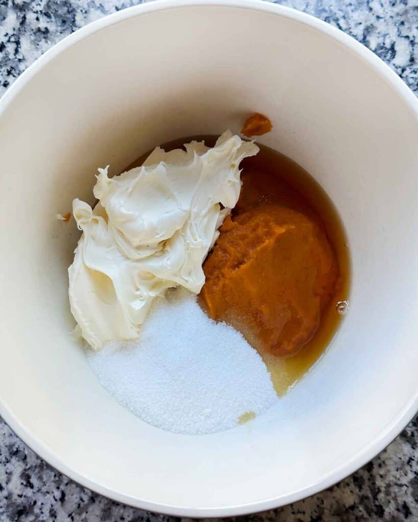 A mixing bowl with pumpkin puree, mascarpone cheese, sugar, and maple syrup.