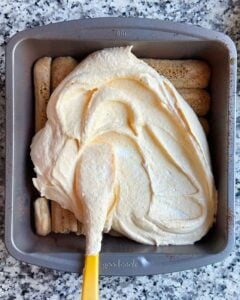 Spreading a pumpkin mascarpone mixture on top of ladyfingers for tiramisu.