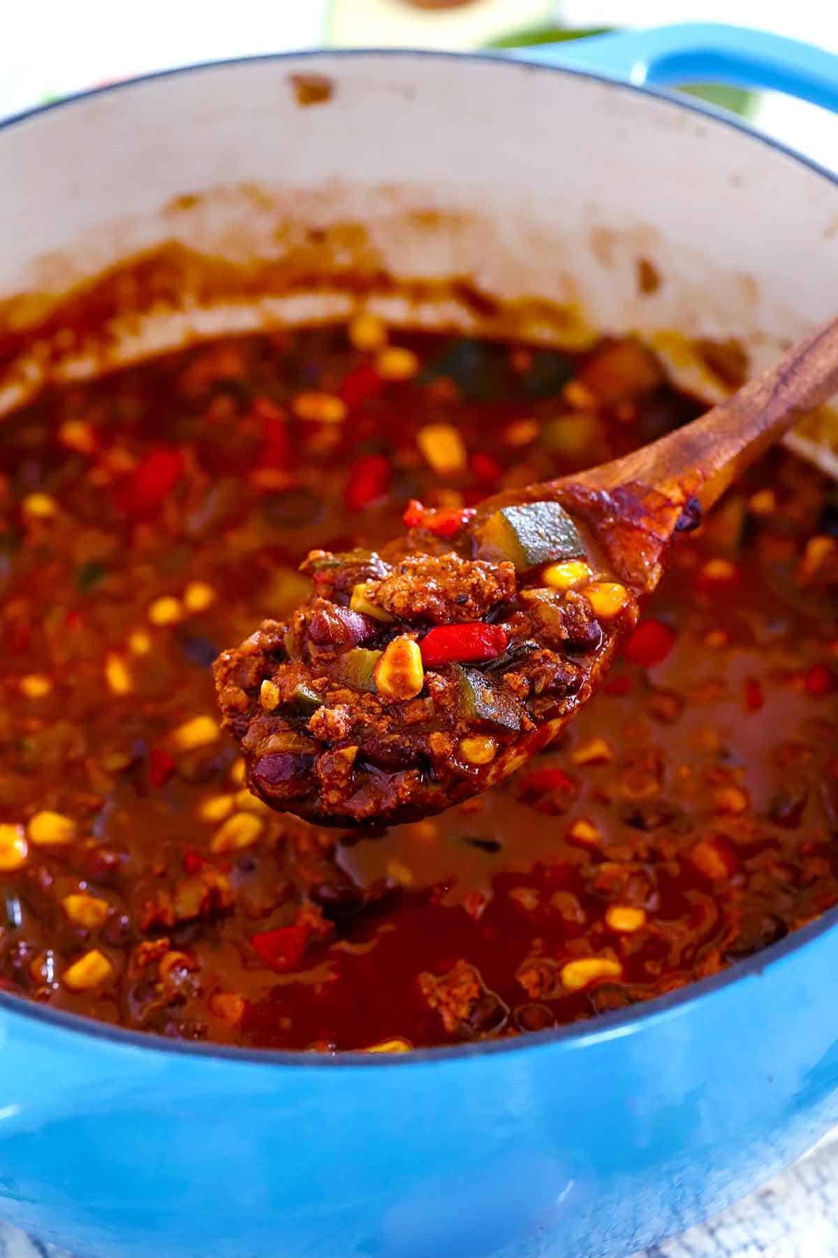 A wooden spoonful of turkey chili with black beans and veggies.