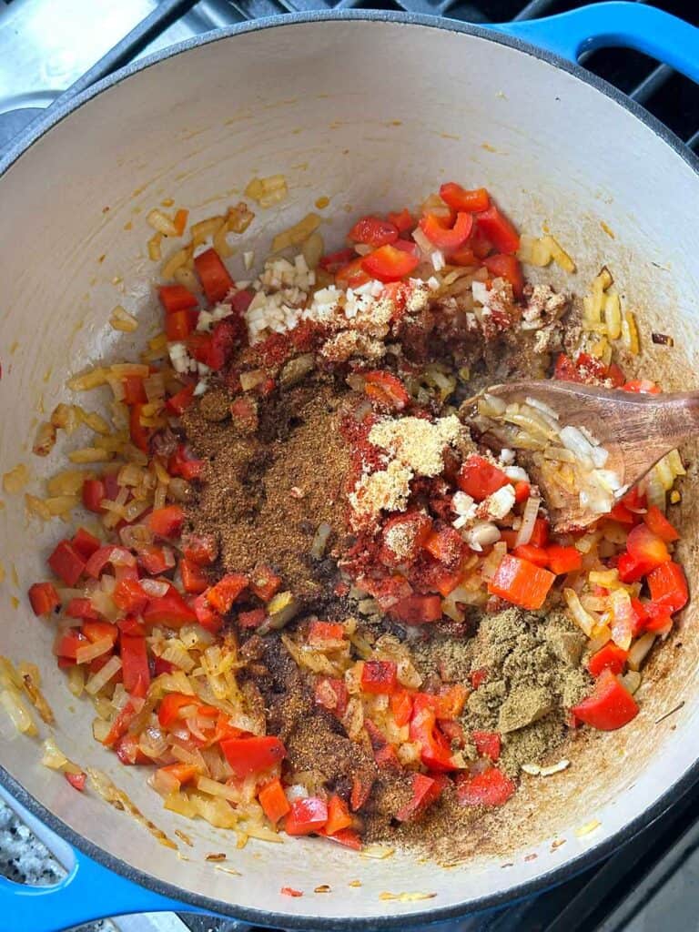 Adding garlic and spices to a pot with peppers and onions for a turkey chili base.