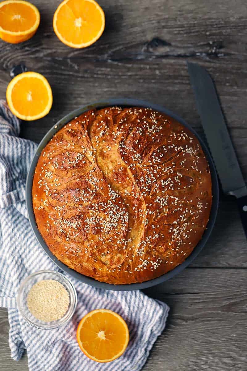 Overhead photo of Greek New Years Bread, or Vasilopita, with sliced oranges around it.