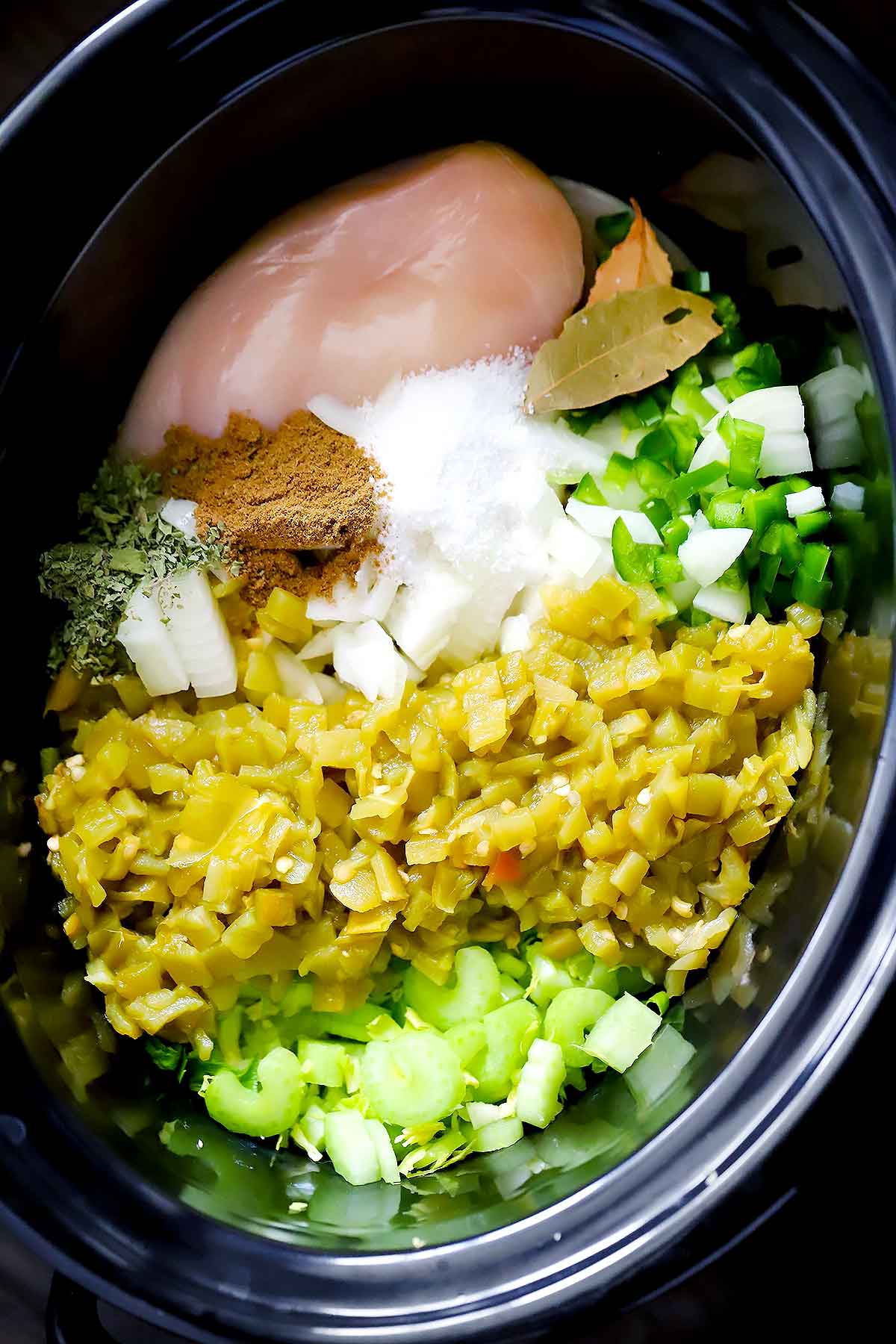 The ingredients for crockpot white chicken chili in a slow cooker.