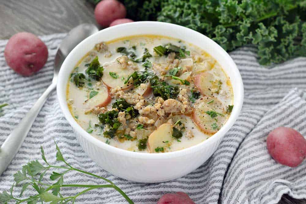 The Olive Garden's famous Zuppa Toscana is so easy to make from scratch at home with only a few ingredients! A creamy, gluten-free soup with Italian sausage, potatoes, and kale.